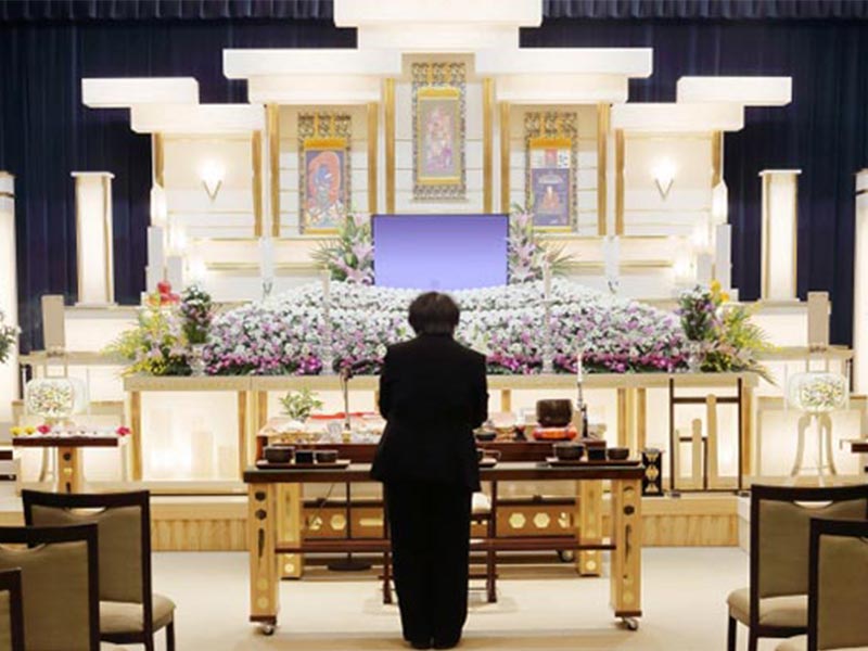 葬儀・告別式で祭壇の前で手を合わせる男性