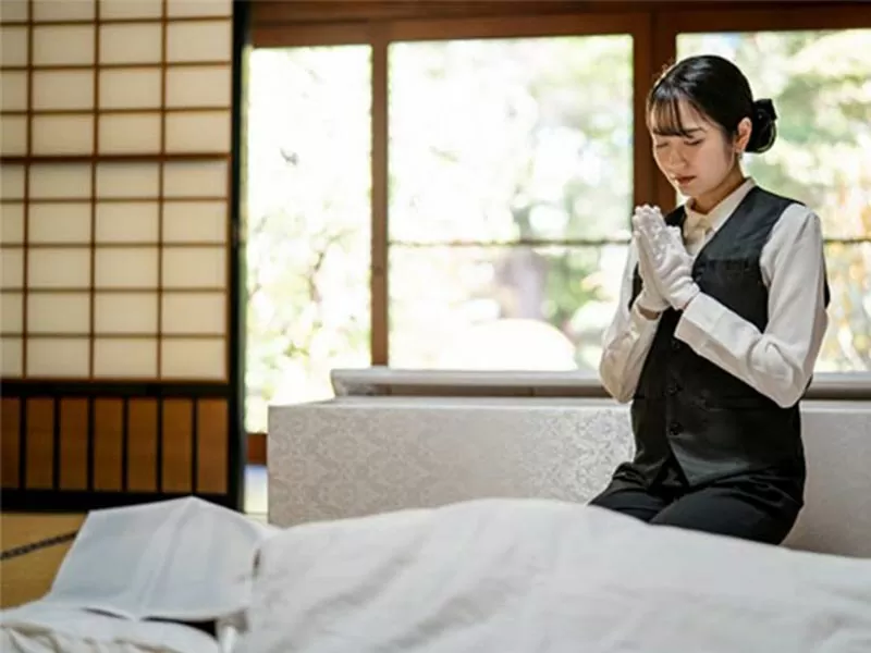 ご遺体の前で手を合わせている葬儀社の女性スタッフ